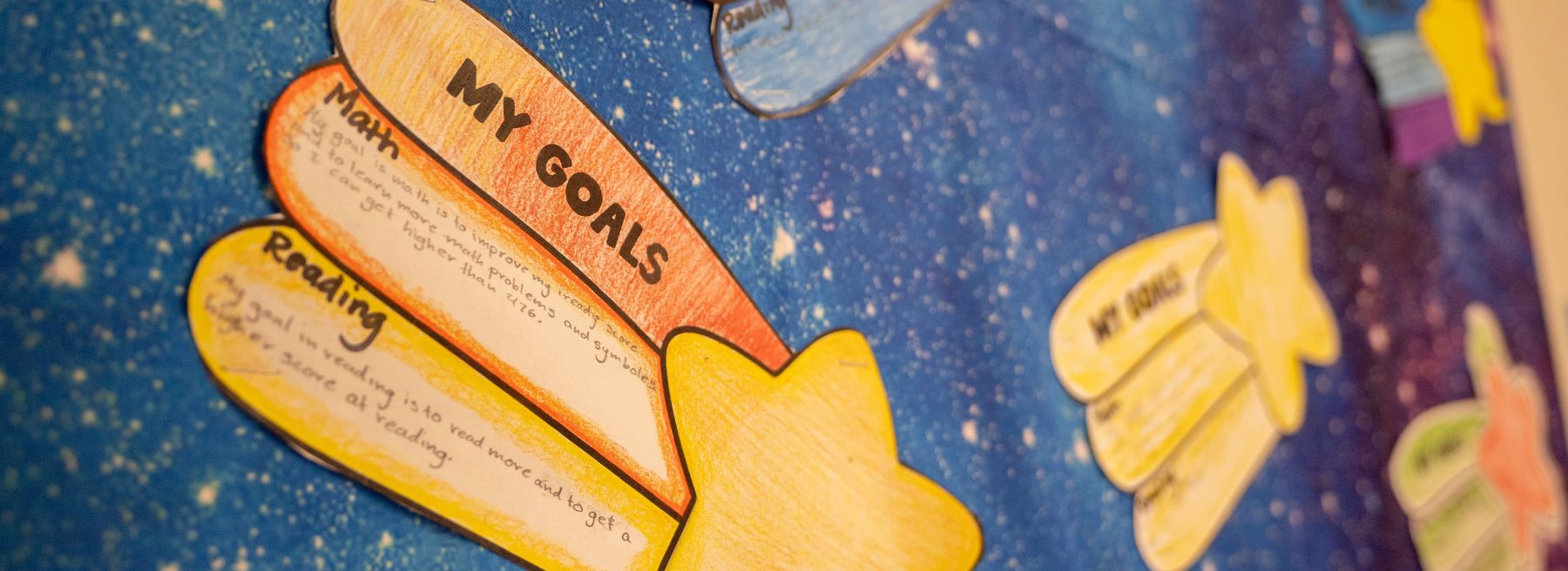 A vibrant wall adorned with numerous colorful paper stars with goals written on them..