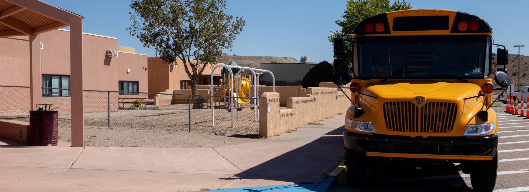 A yellow school bus parked in front of school waiting for students.